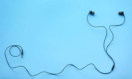 Flat lay of Black Earphones on Blue background