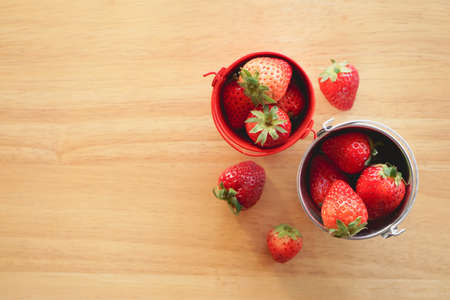 Top view of fresh strawberry in 
small stainless steel water bucket on wooden desk with copy spaceの写真素材