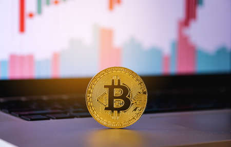 Gold bitcoin on computer laptop with trading graph in the backgroundの写真素材
