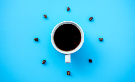 Black coffee cup on blue background with Coffee beans arrang as forming clock faceの写真素材