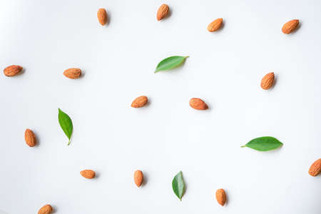 pattern of almonds nuts and green leaves arrange on white backgroundの写真素材