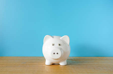 White Piggy bank on blue background with copy spaceの写真素材