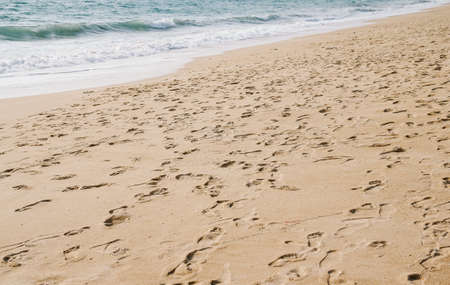 Ocean wave on sandy beach with foot print on sand backgroundの写真素材