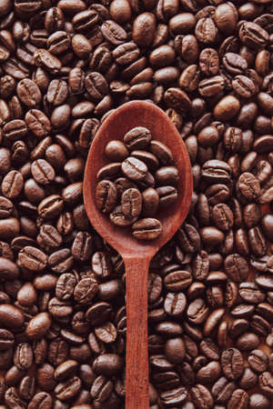 Coffee beans in wooden spoon with coffee bean backgroundの写真素材