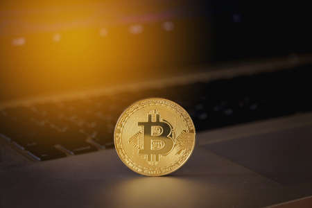 Gold bitcoin on computer laptop with trading graph in the backgroundの写真素材