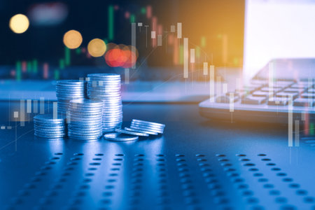 Stack of money coin and laptop computer with trading graph, financial investment concept with blue filter can be use as backgroundの写真素材