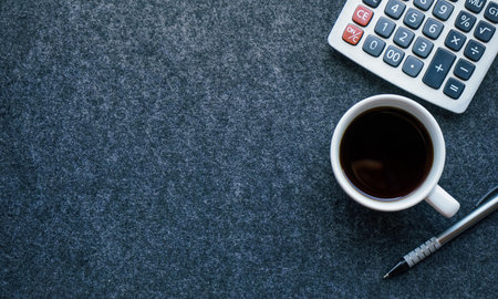 Cup of coffee and calculator on grey background. Top view with copy spaceの写真素材