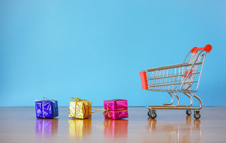 Shopping cart with christmas gift boxes on blue background, online shopping conceptの写真素材