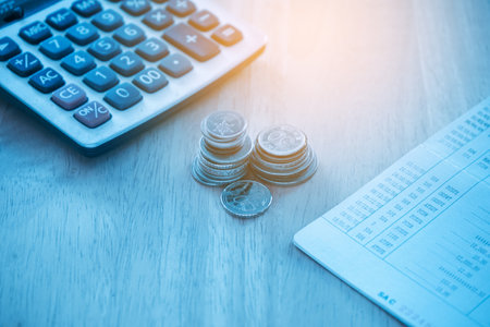 Calculator and stack of coins on wooden table, financial and accounting concept.の写真素材