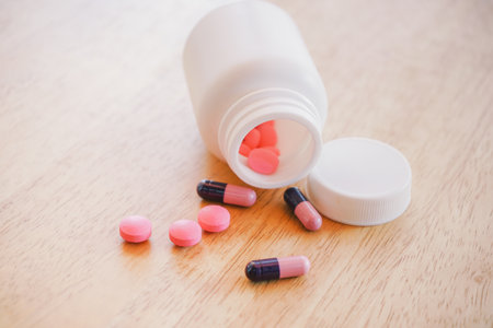 Pills spilling out of pill bottle on wooden background, medical conceptの写真素材