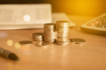 Coins stack and calculator on wooden table with bokeh light background.の写真素材