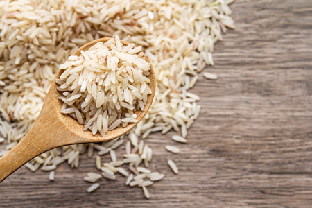 Close up of brown rice in wooden spoon on wooden table background.の写真素材