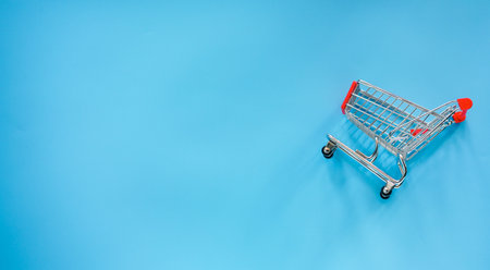 Shopping cart on blue background, top view, copy space.の写真素材
