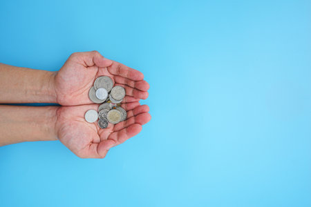 Coins in the hands of a woman on a blue background.の写真素材
