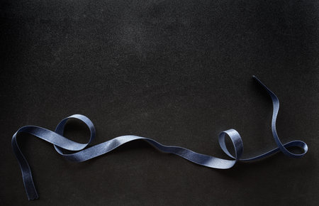 Blue satin ribbon on black background. Top view with copy spaceの写真素材