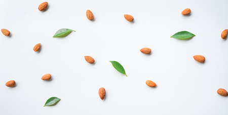 Almond nuts with green leaves on white background. Flat lay, top viewの写真素材