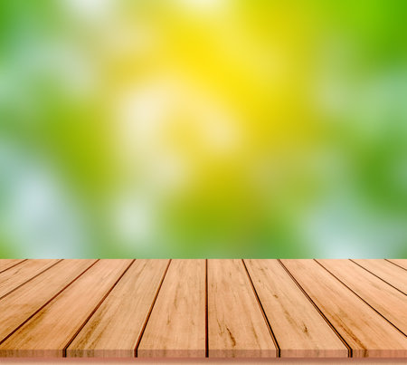 Wooden table top on blurred green and yellow bokeh backgroundの写真素材