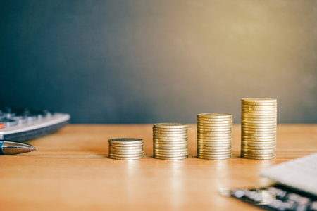 Stacks of coins on the table with laptop and calculator, business and finance conceptの写真素材
