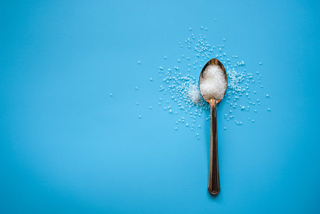 Spoon with sugar on blue background. Top view. Copy space.の写真素材