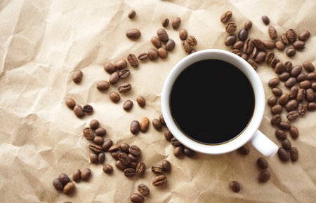 Coffee cup and coffee beans on crumpled paper backgroundの写真素材