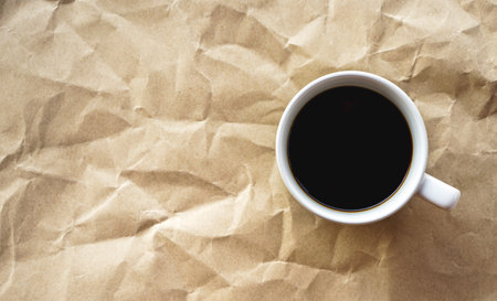 Coffee cup on crumpled paper background, top viewの写真素材