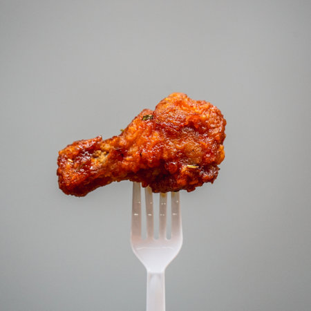 Fried chicken with tomato sauce on a white fork, isolated on gray backgroundの写真素材