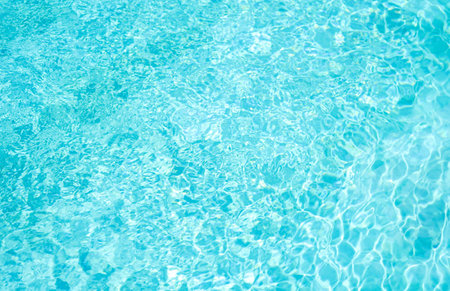 Swimming pool rippled background with sun reflections. Blue waterの写真素材