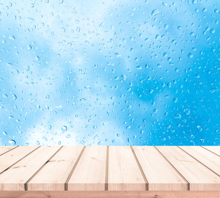 Wood table top on rainy blue sky background - can be used for display or montage your productsの写真素材