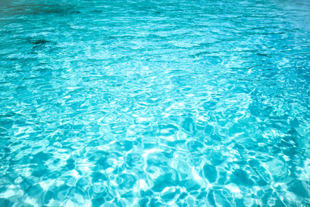 Swimming pool water with sun reflections. Blue water surface background.の写真素材