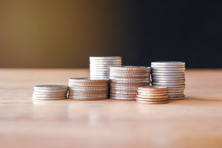 Stacks of coins on wooden table with bokeh background.の写真素材