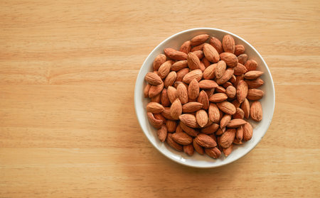 Almond nuts in bowl on wooden table background. Top view.の写真素材