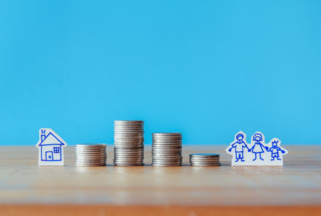 Mortgage concept by house from coins on wooden table with blue backgroundの写真素材