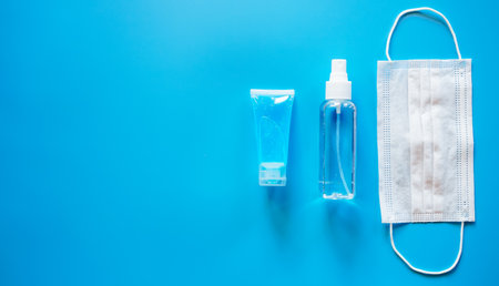 Medical mask and hand sanitizer on blue background top view.の写真素材