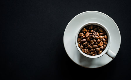 Coffee beans in a white cup on a black background.の写真素材
