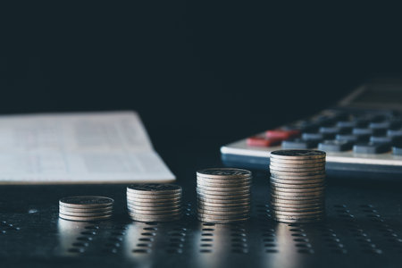 Stack of coins with calculator and book on table, business and finance concept idea.の写真素材