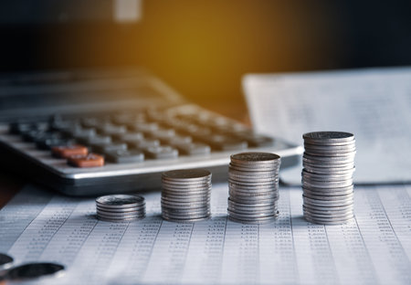 Coins stacked on each other and calculator on finance account book backgroundの写真素材