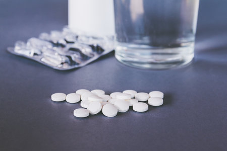 Pills and a glass of water on a gray background. Selective focus.の写真素材