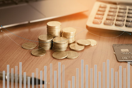 Double exposure of coins stacks and calculator with laptop and credit card on wooden desk, business and financial conceptの写真素材