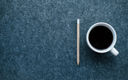 Coffee cup and pencil on dark background. Top view with copy spaceの写真素材