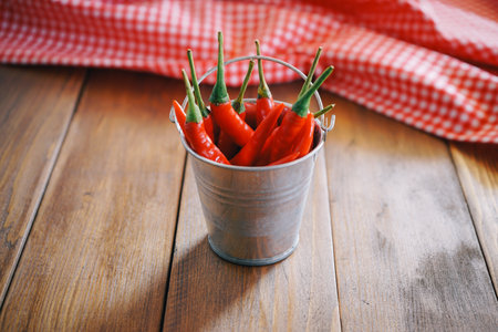 Hot chili peppers in a bucket on a wooden background. Selective focus.の写真素材