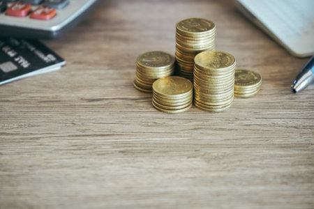 Stack of coins and calculator on wooden table, business and finance conceptの写真素材