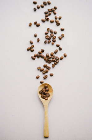 Coffee beans in a wooden spoon on white background. Top view.の写真素材