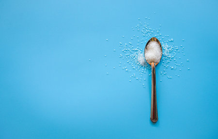 Sugar in a spoon on a blue background with copy space.の写真素材