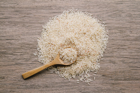 Raw rice in wooden spoon on wooden background. Top view. Copy space.の写真素材