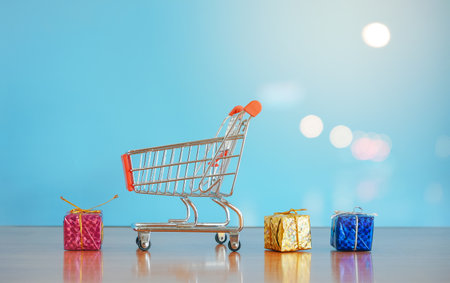 Shopping cart with gift boxes on blue background with copy space.の写真素材