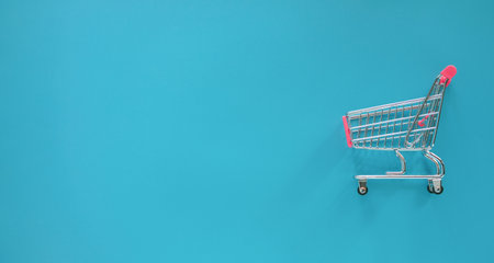 Empty shopping cart isolated on blue background with copy space for text.の写真素材