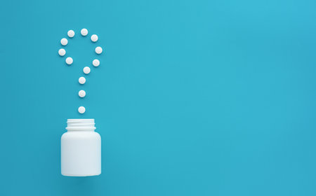 White pill bottle with question mark on blue background with copy space. Medicine concept.の写真素材