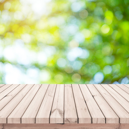 Wooden table top on blur green bokeh background - can be used for display or montage your productsの写真素材