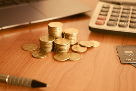 Coins and credit card on the desk with laptop, business conceptの写真素材
