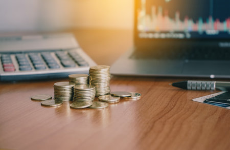 Coins stack on table with laptop computer and calculator for finance and banking concept.の写真素材